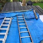 2 silver ladders on a flat roof extension with a blue waterproof cover on